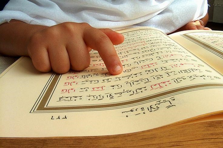 A child reading Quran pointing out the Ayah