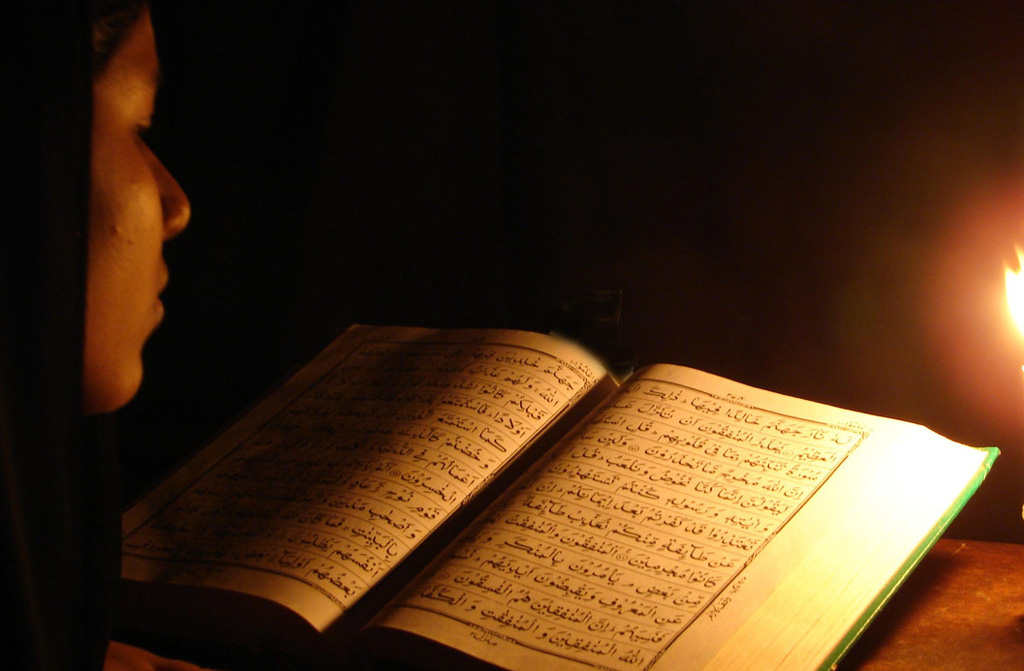 A man reading Quran in darkness with a deep concentration