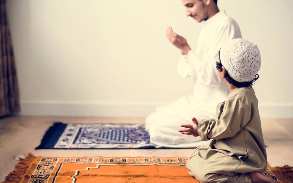 A man with his child praying after finishing Salat 