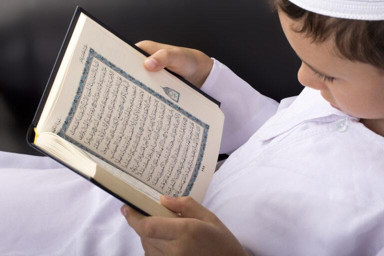 A kid reading from a Mushaf