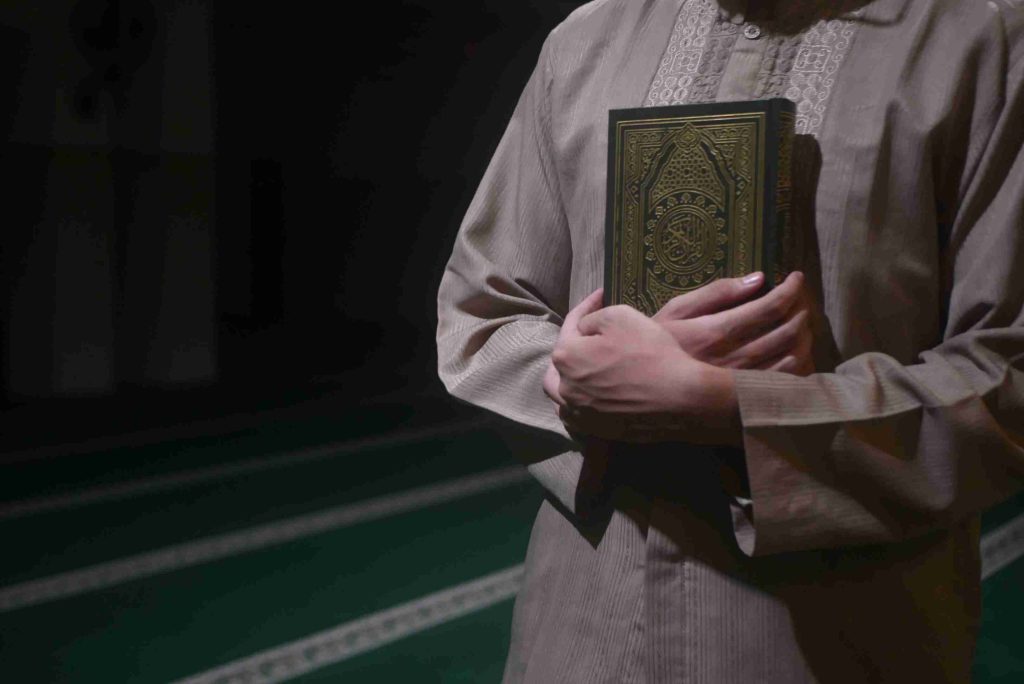 A boy hugging a copy of the Quran