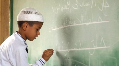 a boy writes Arabic